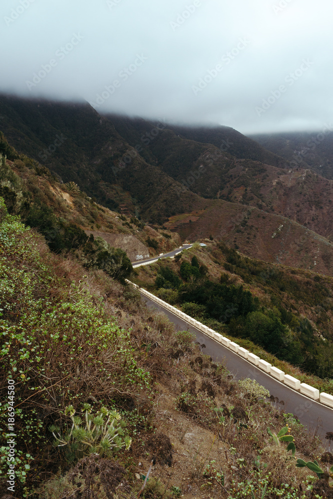 Empty road on hillside in mountains covered in clouds Empty road on hillside in mountains covered in clouds