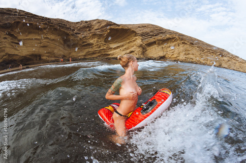 Young topless girl in thongs on pool float in ocean waves photo
