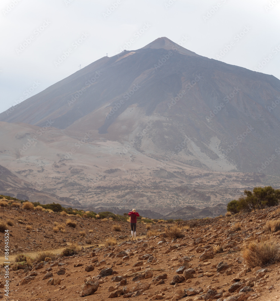 Girl walking in desert with volcano in background