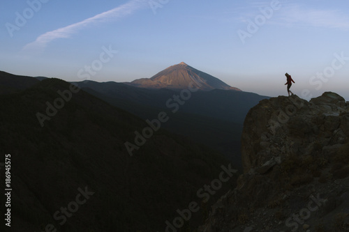 Fototapeta Naklejka Na Ścianę i Meble -  Woman standing on the cliff with volcano in the background