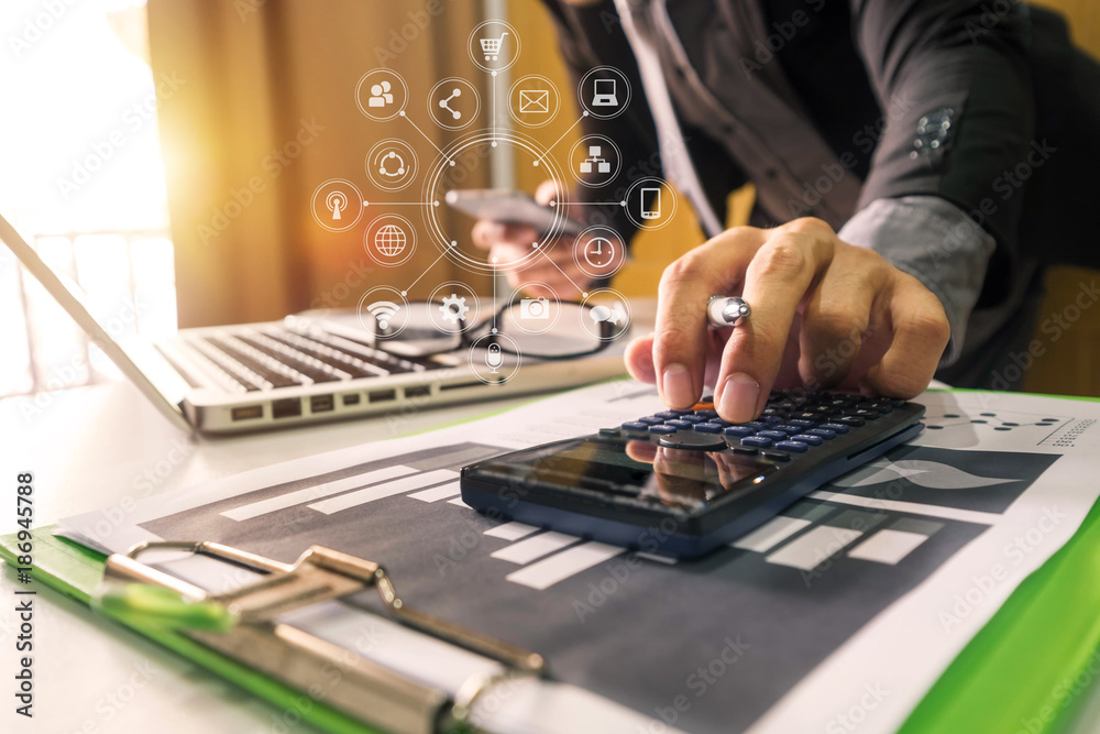 Fototapeta premium businessman hand working with finances about cost and calculator and laPtop with tablet and smartphone on withe desk in modern office in morning light 