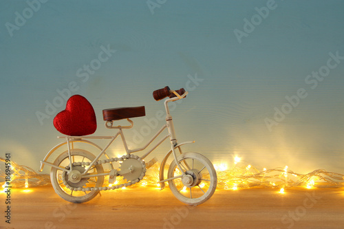 Valentine's day romantic background with white vintage bicycle toy and heart on it over wooden table. © tomertu
