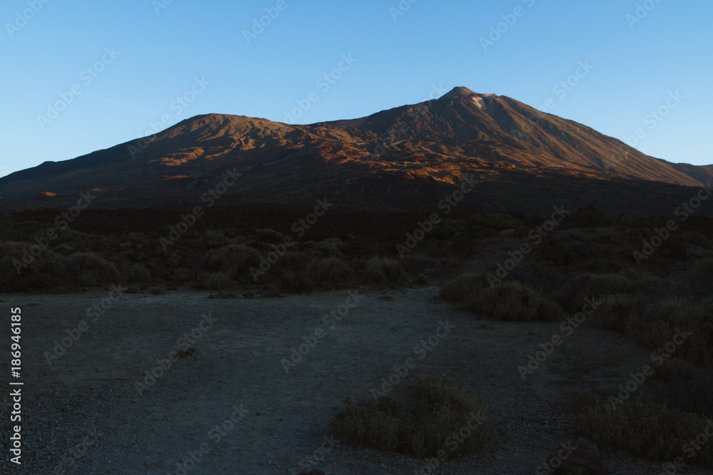 Sunrise light on volcano in desert landscape