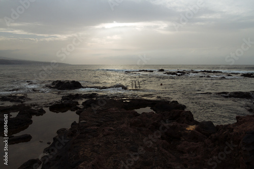 Ladder to ocean on rocky beach in cloudy weather