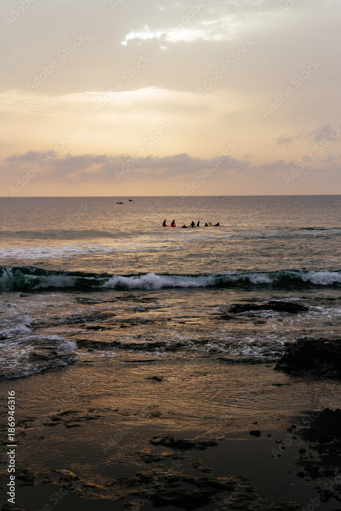 Surfers in ocean waiting for waves while sunset
