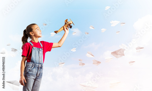 Concept of careless happy childhood with girl throwing retro plane © adam121