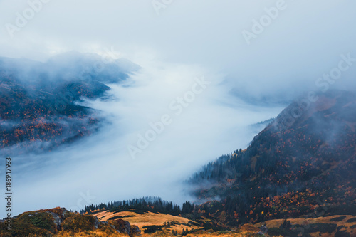 mountain landscape with fog below the peaks and clouds above them in blue tones © dziewul