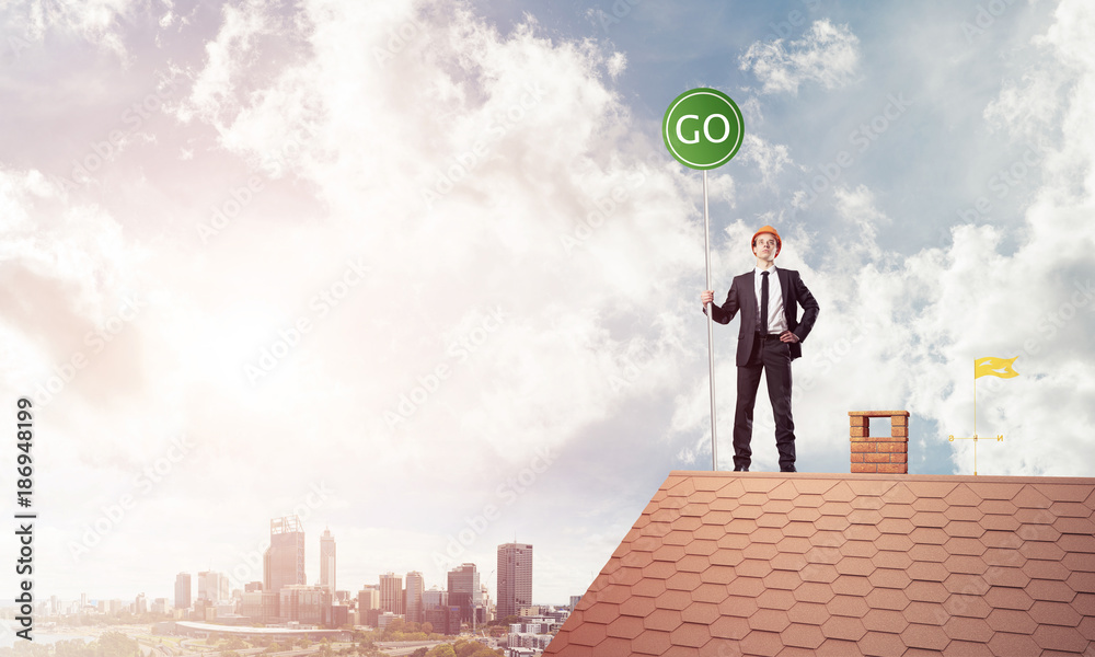 Businessman in suit on house top with ecology concept signboard. Businessman in suit on house top with ecology concept signboard.