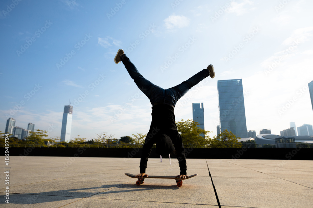 female skateboarder doing a handstand on skateboard in city