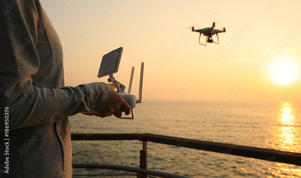 Fototapeta premium silhouette of remote control a flying drone which taking photo over sunrise sea