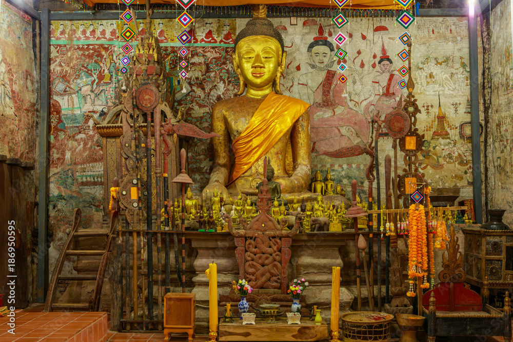 Fototapeta premium The wooden Buddha statue in the old buddhist temple 300 year old in the countryside of Thailand.