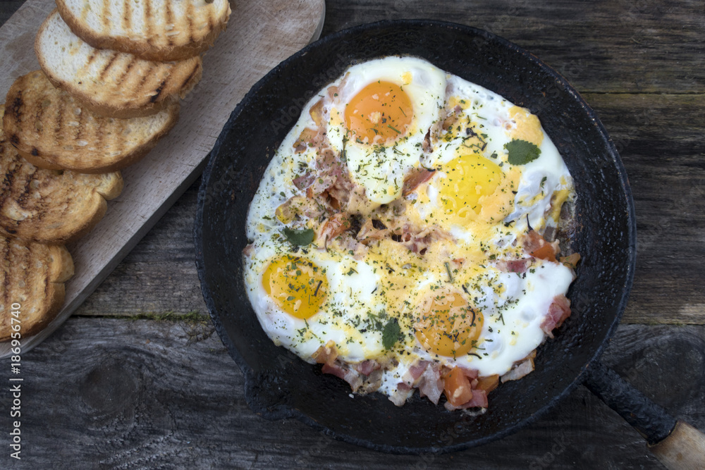 Fried eggs in an old frying pan and fried bread on a wooden background. Fried eggs in an old frying pan and fried bread on a wooden background.