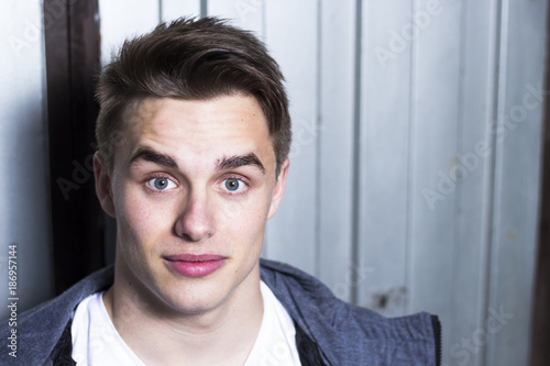 Young handsome man with surprised face expression and metal garage door background.