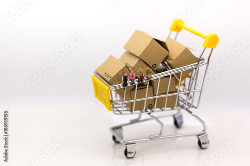 Miniature people , people sitting on shopping cart with paper box in shopping cart , using as background marketing, business online concept.