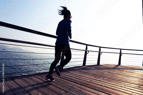 sporty female jogger morning exercise on seaside boardwalk during sunrise