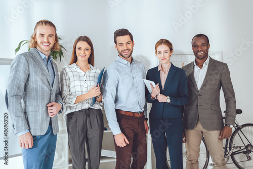 smiling multicultural businesspeople standing and looking at camera