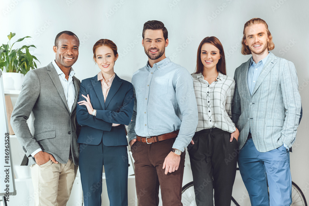 Fototapeta premium smiling multicultural businesspeople standing and looking at camera