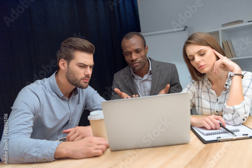 business team have discussion while sitting at table with laptop