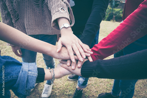 Top view image of group of young people putting their hands together. Friends with stack of hands showing unity.