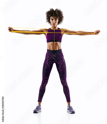 Sportswoman performs exercises for the muscles of the chest. Photo of young woman workout with resistance band isolated on white background. Strength and motivation.