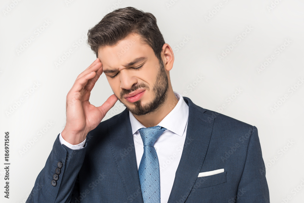 young businessman suffering from headache isolated on grey young businessman suffering from headache isolated on grey