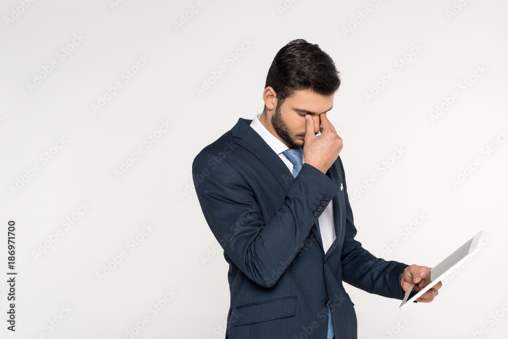 tired young businessman holding digital tablet isolated on grey tired young businessman holding digital tablet isolated on grey