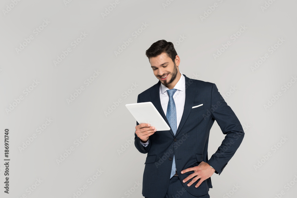 smiling young businessman holding digital tablet isolated on grey smiling young businessman holding digital tablet isolated on grey