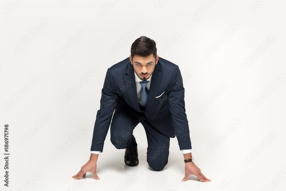 serious young businessman in starting position ready to run isolated on grey serious young businessman in starting position ready to run isolated on grey