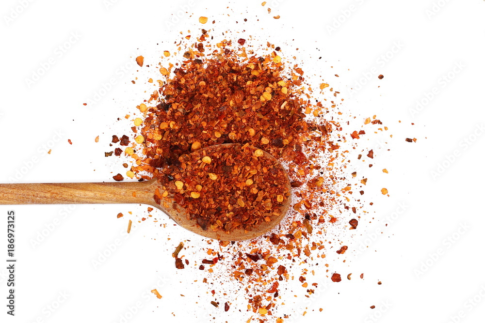 Crushed red cayenne pepper, dried chili flakes, seeds pile and wooden spoon isolated on white background Crushed red cayenne pepper, dried chili flakes, seeds pile and wooden spoon isolated on white background