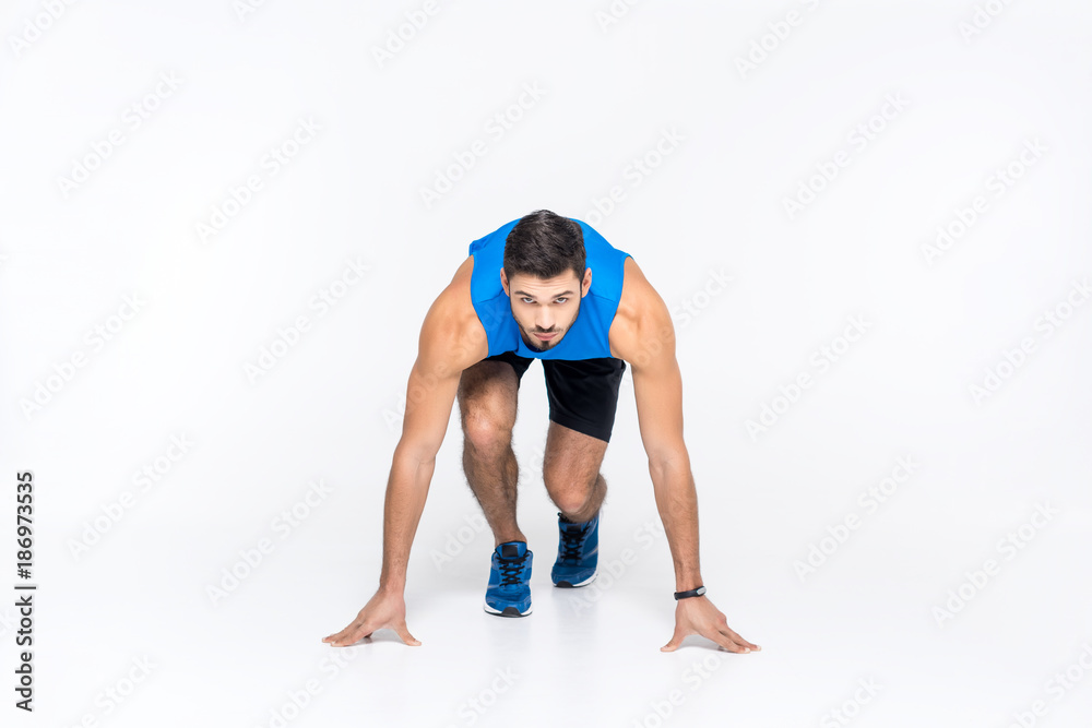handsome young sprinter in start position isolated on white