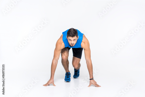 handsome young sprinter in start position isolated on white