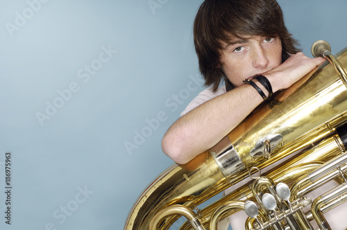 Portrait of teenage boy with tuba in front of blue background