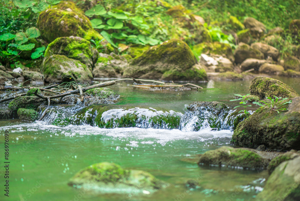  Small mountain waterfall on the rocks covered with moss deep in the forest. Cliffs in Cheile Turzii, Romania. Autumn is coming. Beautiful, calming nature background