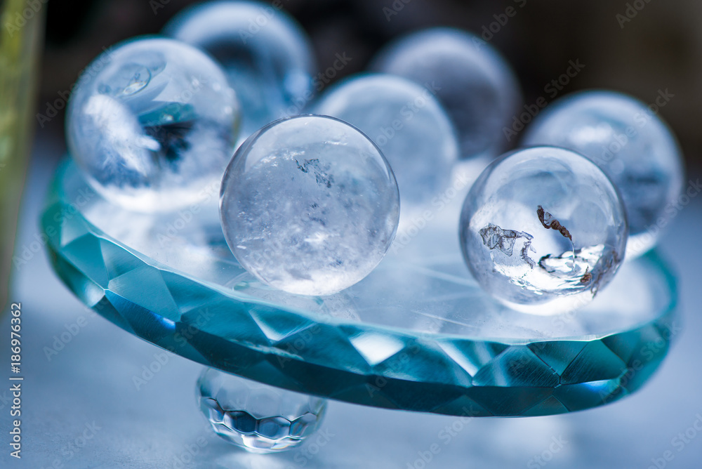Macro shot of transparent crystal balls with colorful ornaments and sun reflections in it, on turquoise glass pad. Fortune telling. Love, money, luck, success Macro shot of transparent crystal balls with colorful ornaments and sun reflections in it, on turquoise glass pad. Fortune telling. Love, money, luck, success