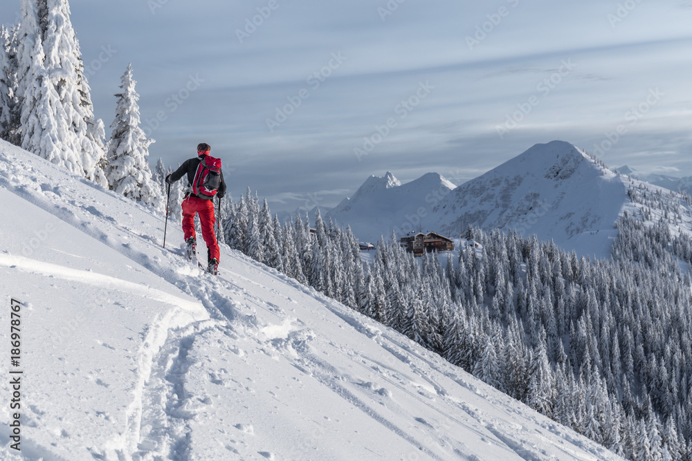 Aufstieg eines Mannes beim Skitouren gehen im Gebirge mit Berge im Hintergrund