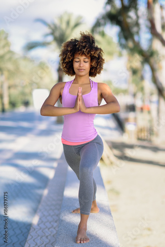 Black woman, afro hairstyle, doing yoga in the beach © javiindy