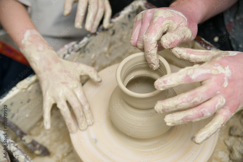 Hands of a potter, creating a pot of clay