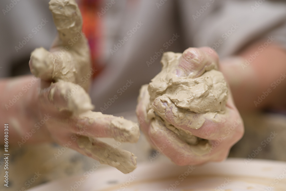 Hands of young potter kneading clay
