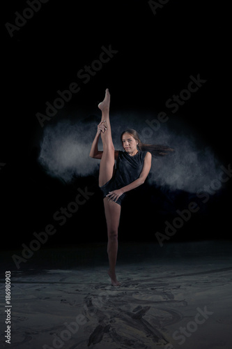 The girl gymnast makes a gymnastic sketch with flying powder. Sport. Dance. © semenenkostas
