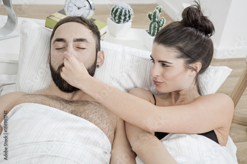 Couple lying in bed with man snoring photo