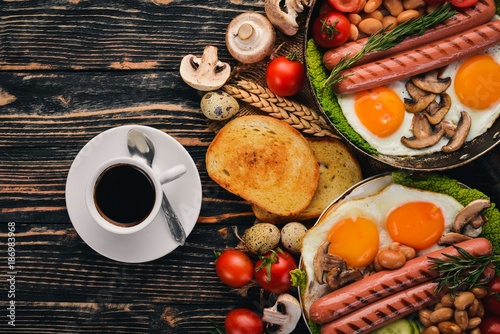 English breakfast - fried egg, beans, tomatoes, mushrooms, bacon and toast. Top view. On a wooden background.