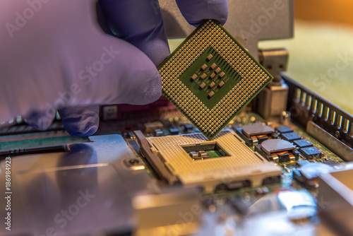 Serious processor security hole. CPU vulnerability. A hand holds a processor in front of a processor slot. Focus on the processor. Concept: cyber security