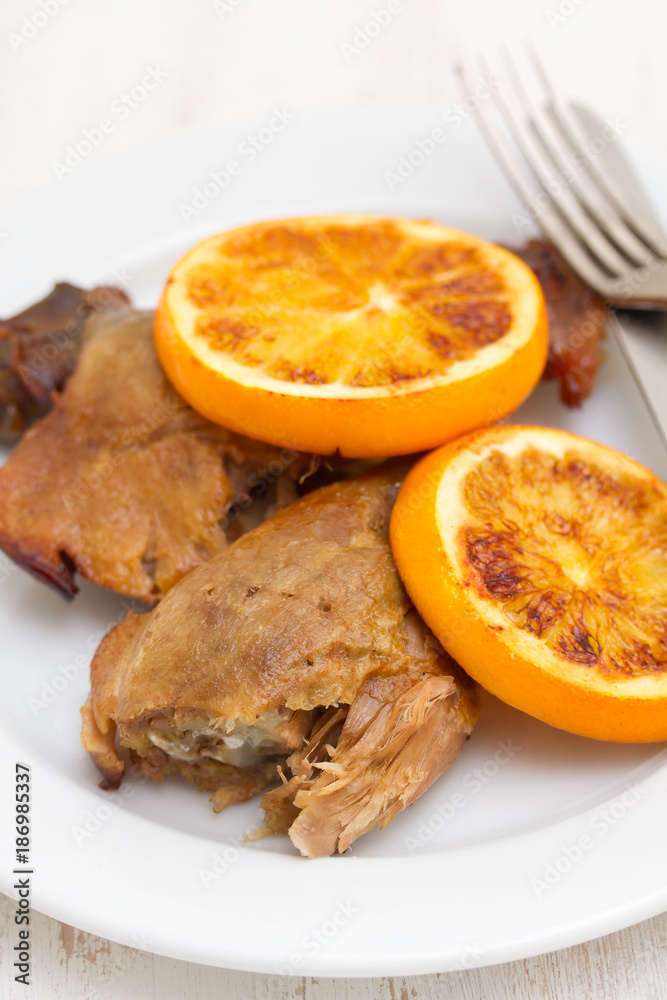 baked duck with orang on white dish with fork and knife baked duck with orang on white dish with fork and knife
