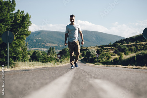Young man looking at the camera in the middle of the road surrounded by nature in the countryside in Madrid, Spain photo