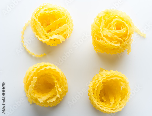 vivid yellow fettuccine pasta on white plate on white background with shadow