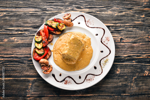 Meat steak with sauce and grilled vegetables. Steak Voronov. On a wooden background. Free space for your text. Top view. photo