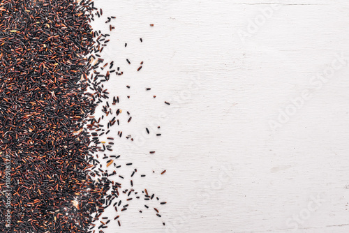 Black dry rice. On a wooden background. Top view. Copy space.