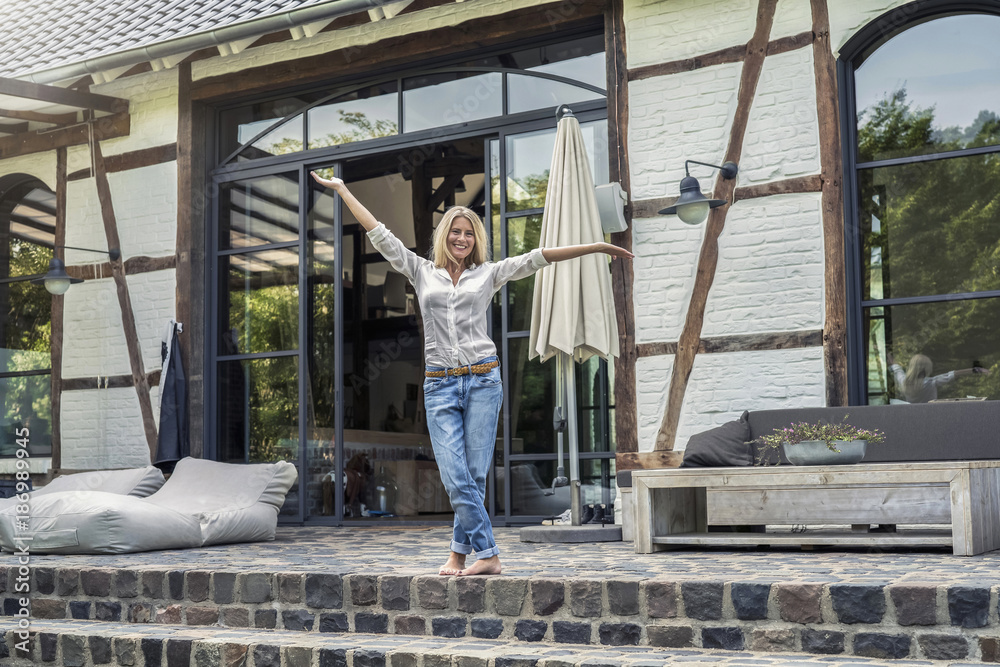 Happy owner standing in front of her country house Happy owner standing in front of her country house