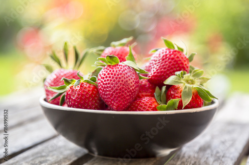 Bowl of strawberries on wooden garden table photo