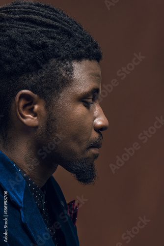 side view of handsome african american man with dreadlocks isolated on brown